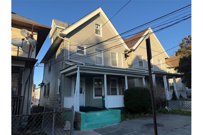 View of front of home with covered porch and fence