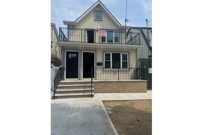 View of front of house with stucco siding and a balcony