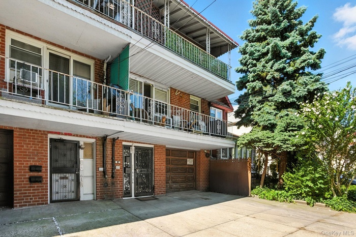 View of exterior entry featuring brick siding, a garage, and driveway