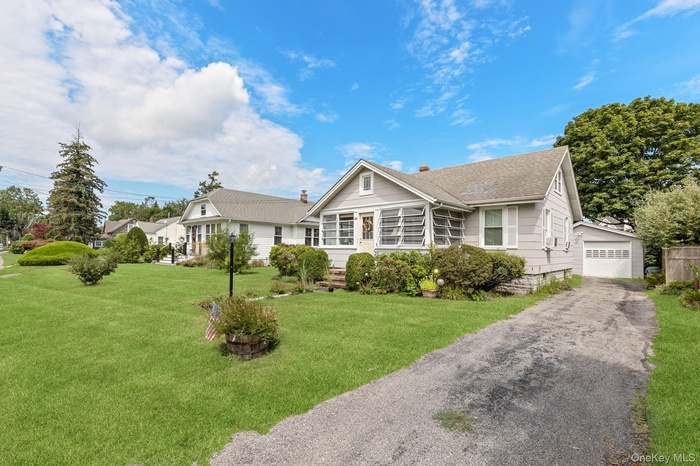 View of front of home with a front lawn, roof with shingles, and an outbuilding