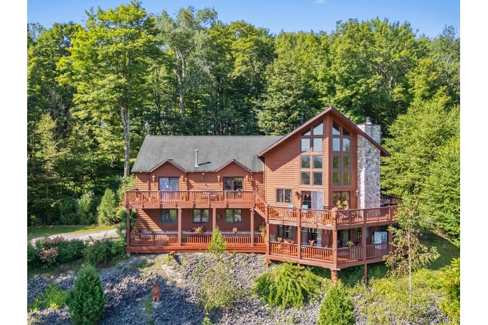 Front view of property with a deck, a chimney, and a forest view