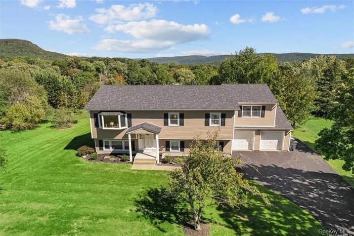 Split foyer home featuring a forest view, an attached garage, and a front lawn