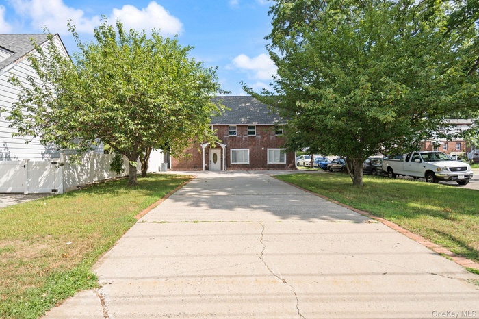 View of front of home with brick siding, a front yard, and concrete driveway