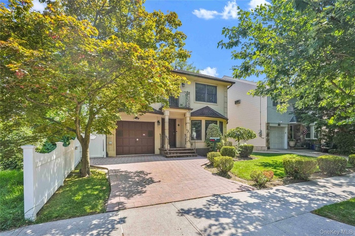 View of front of house with decorative driveway, a balcony, and a garage