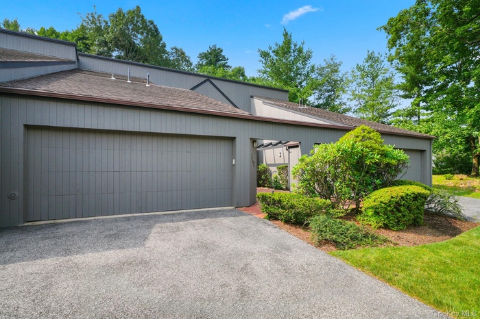 Mid-century inspired home with driveway, an attached garage, and a shingled roof