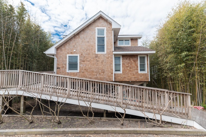 Back of property featuring a wooden deck and roof with shingles