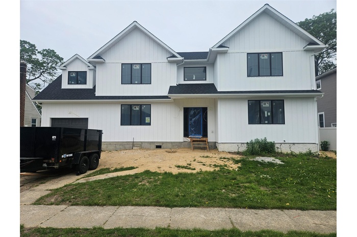 Modern farmhouse featuring entry steps, a shingled roof, and a front lawn