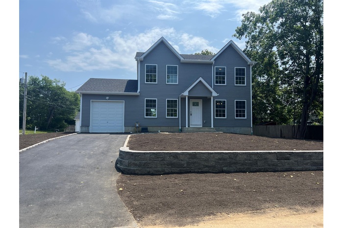 View of front of property featuring an attached garage, driveway, and a shingled roof