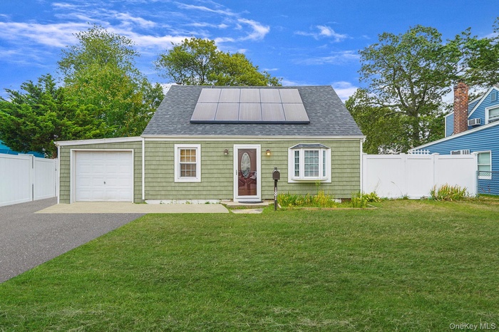 View of front of property featuring roof mounted solar panels, a garage, asphalt driveway, and roof with shingles