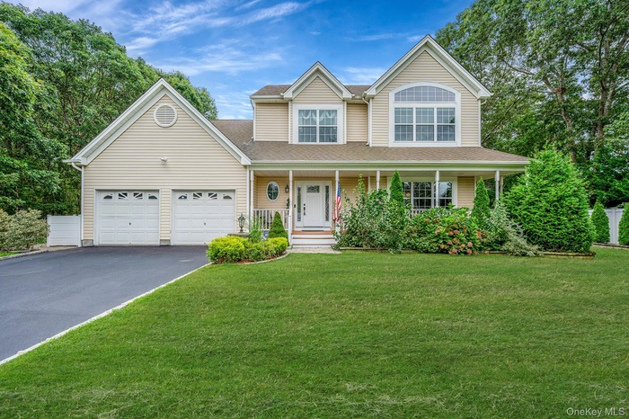 View of front of house with driveway, an attached garage, a porch, and a front yard