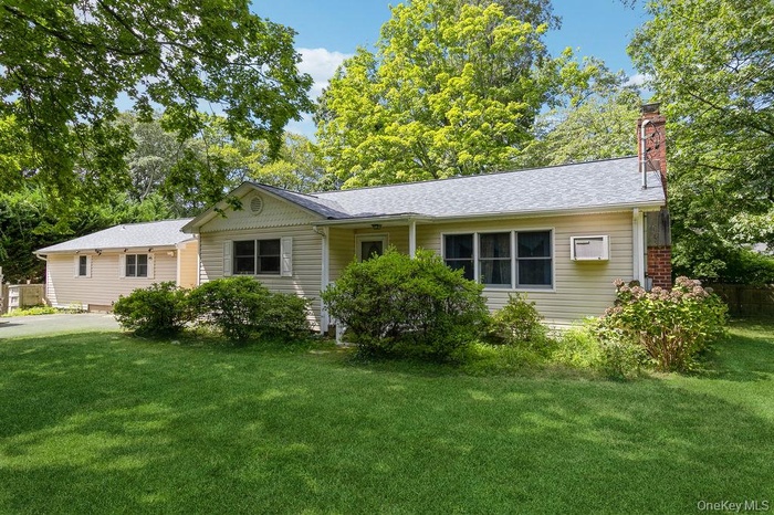 View of front of house featuring a chimney, a front lawn, and a shingled roof