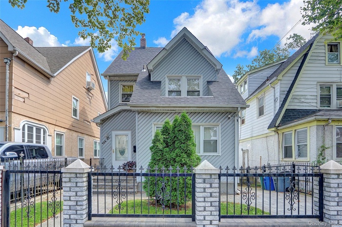 View of front of property with a fenced front yard, a shingled roof, and a gate