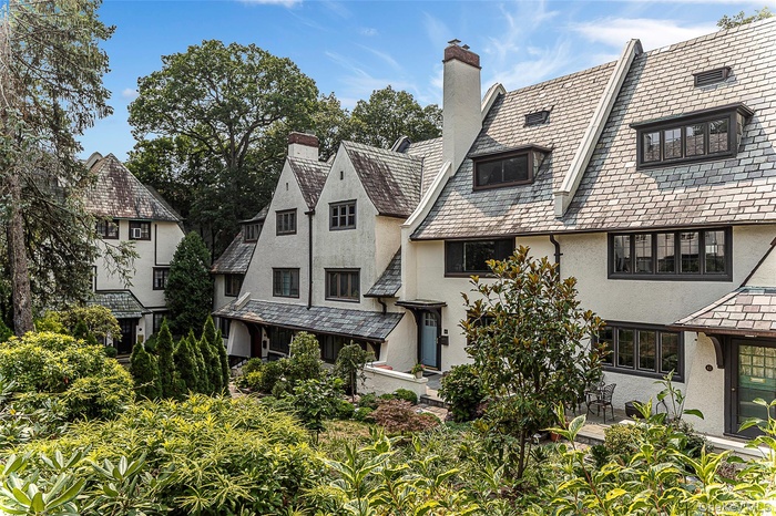 View of front of home featuring a high end roof, stucco siding, and a chimney