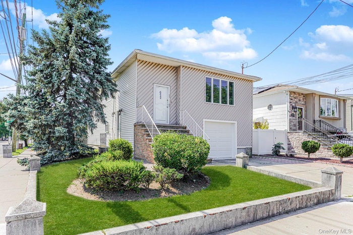 View of front facade with a garage, a front lawn, and concrete driveway