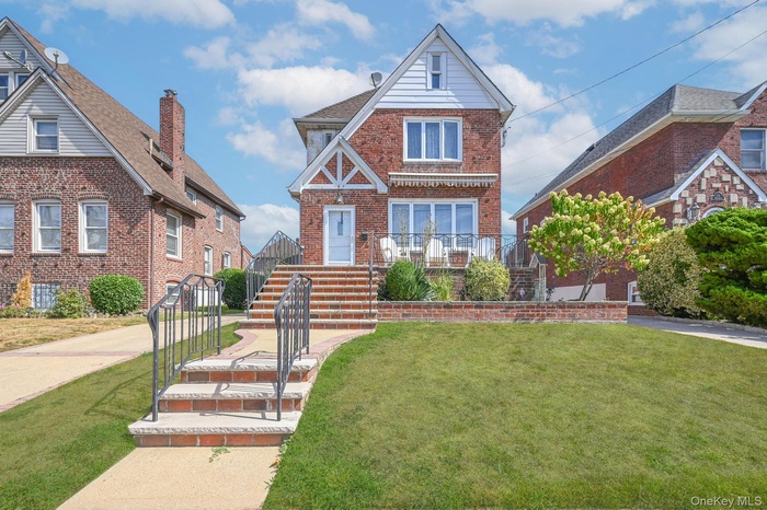 English style home featuring brick siding, a front yard, and stairs