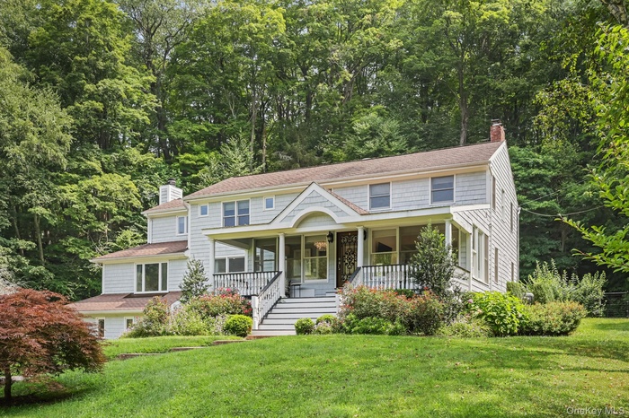 View of front of house featuring a chimney, covered porch, and a front lawn