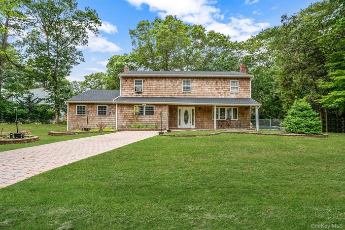 View of front facade featuring a chimney, a front lawn, and covered porch