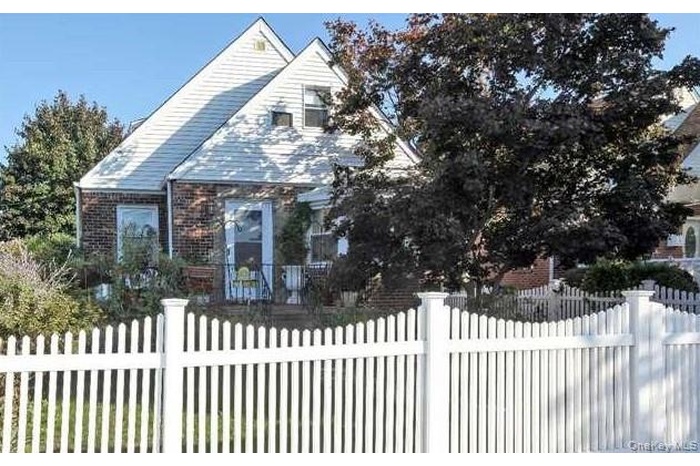 Bungalow-style house with a fenced front yard and brick siding