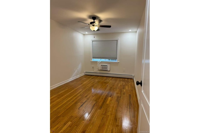 Spare room with wood finished floors, a baseboard heating unit, a ceiling fan, recessed lighting, and an AC wall unit