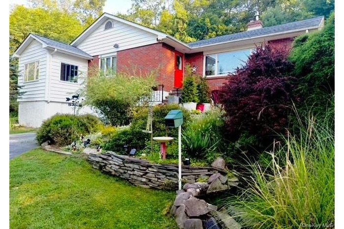 View of front facade featuring brick siding, a chimney, and a front lawn