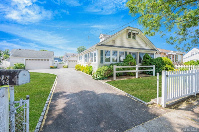 Bungalow featuring a fenced front yard, a sunroom, a garage, and an outdoor structure