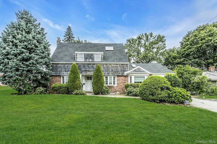 View of front of house featuring brick siding, a front lawn, and a chimney