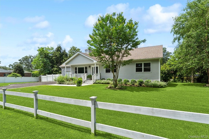 View of front facade featuring covered porch, asphalt driveway, and a chimney
