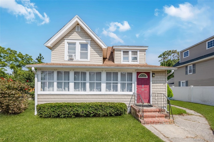 View of front of house with a front yard and a shingled roof