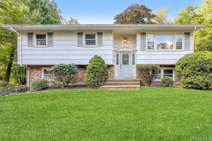 Raised ranch with brick siding and a front yard