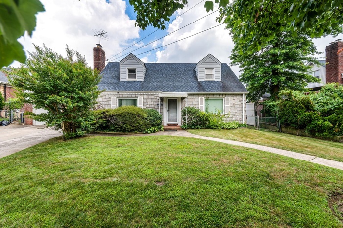 Cape cod-style house featuring stone siding, a chimney, and roof with shingles