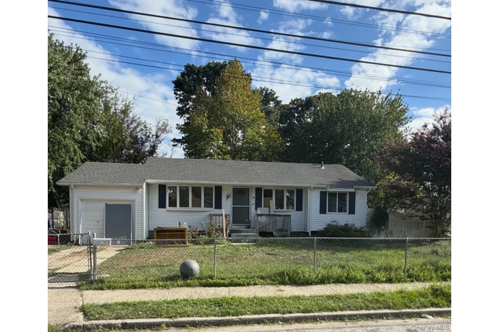 Ranch-style house featuring an attached garage, a fenced front yard, a gate, driveway, and a shingled roof