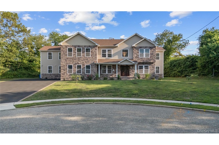 Craftsman-style home with stone siding, a front lawn, driveway, and a porch
