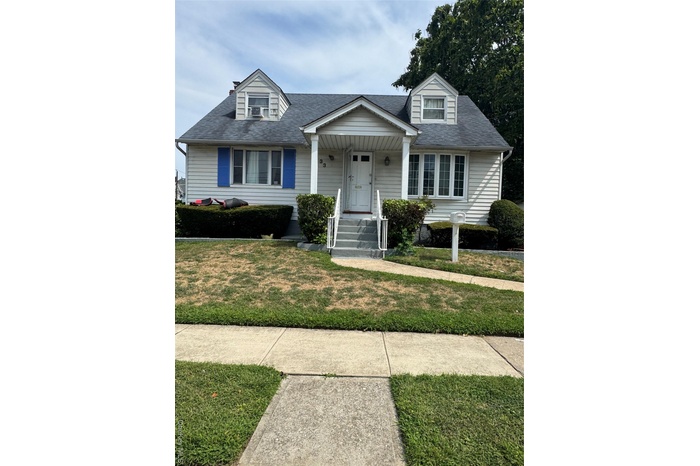 View of front of house with a shingled roof, a porch, and a front lawn