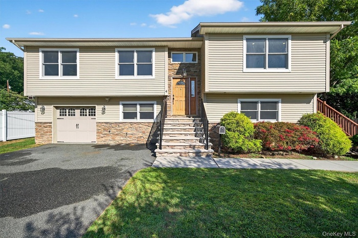 Split foyer home with stone siding, driveway, and a garage