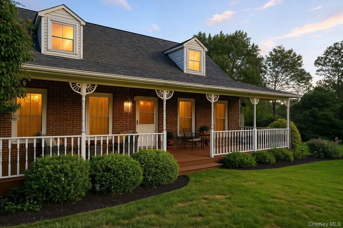 View of front of home featuring brick siding, a porch, a shingled roof, and a front lawn