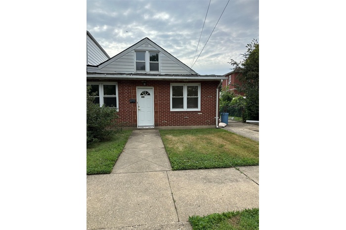 View of front of property featuring brick siding and a front yard