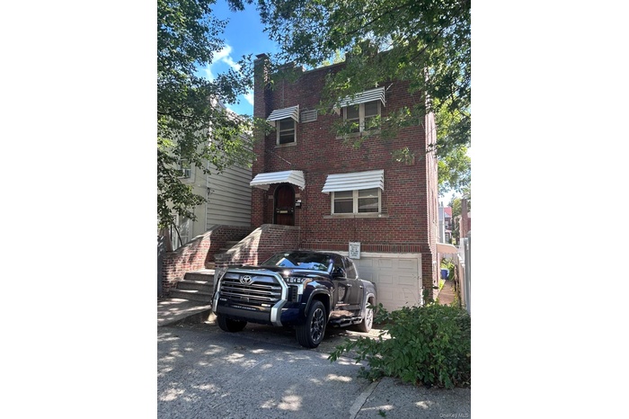 View of front facade featuring brick siding, a chimney, and an attached garage