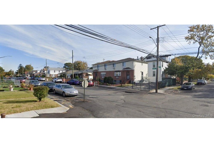 View of asphalt road featuring a residential view, curbs, sidewalks, traffic signs, and street lights