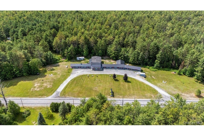 Aerial view of property and surrounding area featuring a forest