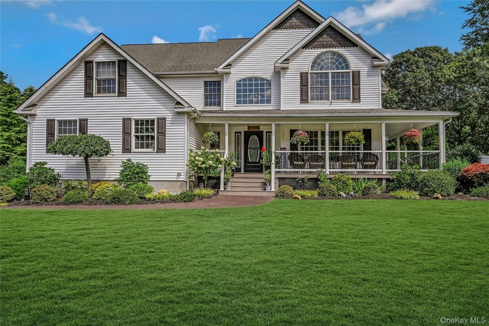 View of front of home with a porch, a front lawn, and a shingled roof