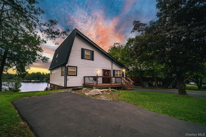 View of front facade featuring a lawn and a deck