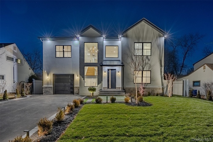 View of front of property featuring stone siding, driveway, a garage, stucco siding, and a gate