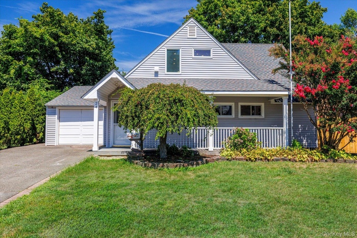 View of front facade with roof with shingles, a front yard, and driveway