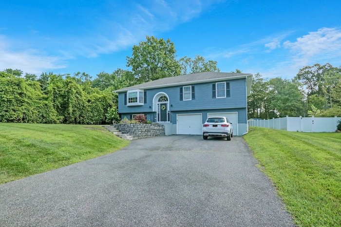 Bi-level home with an attached garage and asphalt driveway