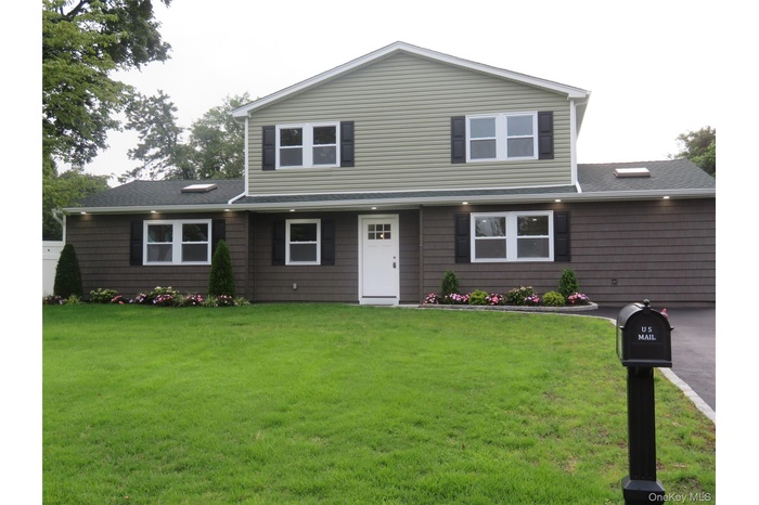 View of front of property featuring a front yard and roof with shingles