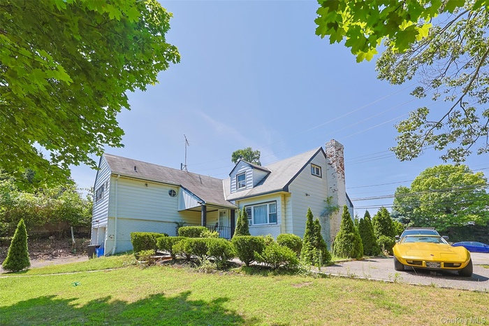 View of front of house with a chimney, a front lawn, and brick siding