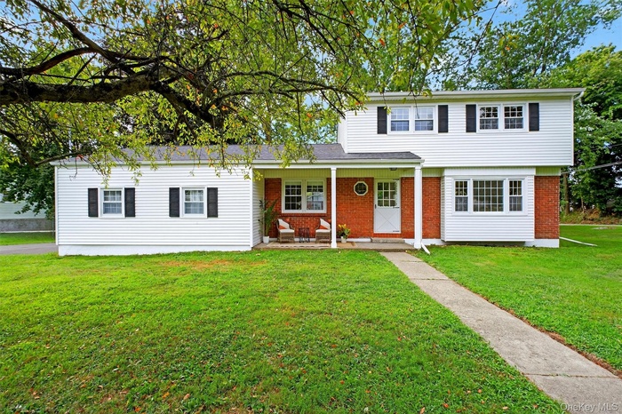 View of front of house with a front yard, brick siding, and a patio