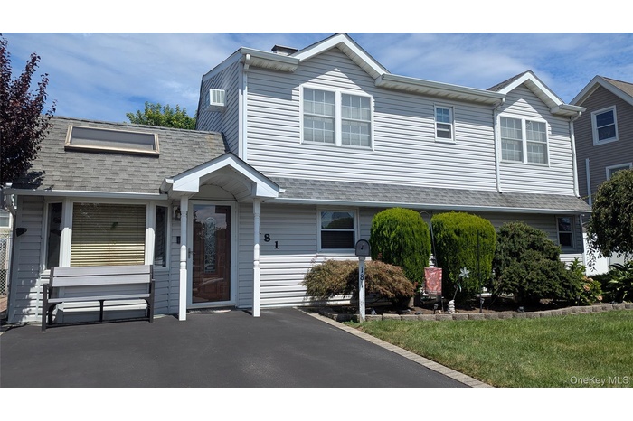 View of front of house with a shingled roof and a front yard