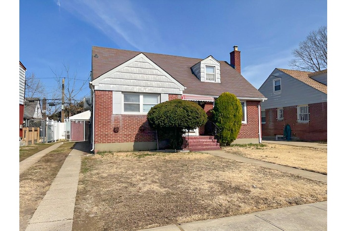 View of front of property with brick siding and a chimney