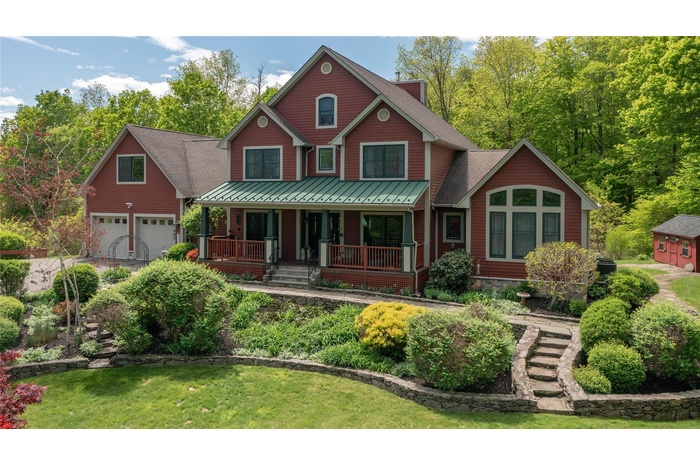 View of front of property with covered porch and beautiful landscaping